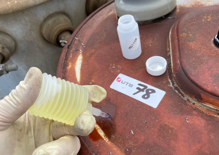 A person holding a bottle of yellow liquid labeled 'MCF Waukesha Sample.