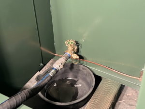 A hose connected to a bucket and a green metal box. Reconditioning Resolves Oil Leaks.