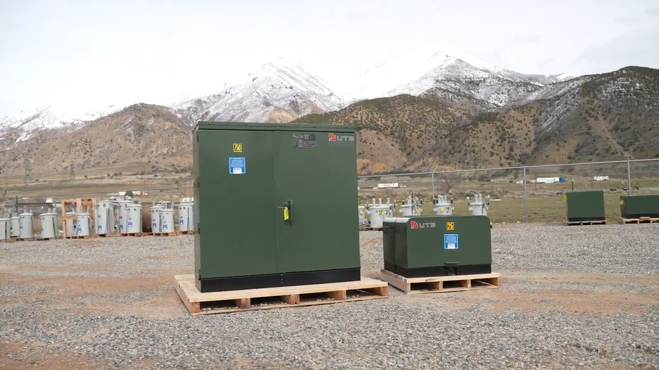Two green electrical power generators on pallets, set against a backdrop of majestic mountains